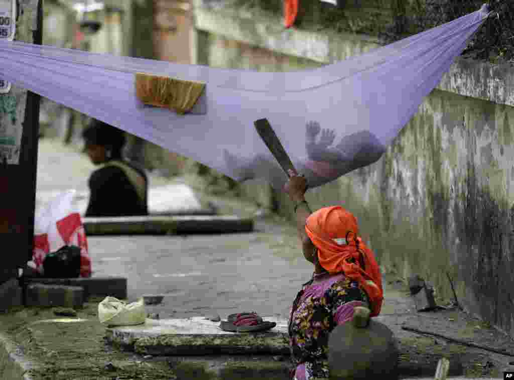 یک زن کارگر در خیابانی در بمبئی هند، مشغول خواباندن کودکش است.