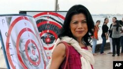 FILE - In this Nov. 18, 2012, file photo, activist Theary Seng poses with dartboard posters during a protest in Phnom Penh, Cambodia. (AP Photo/Luke Hunt, File)