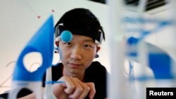 (FILE)An exhibition staff moves a styrofoam ball with wind from a fan controlled by his brain waves, as he demonstrates using an exhibit called "Mindflex" during a photo opportunity at the Smart City 2013 International Design Exhibition in Beijing October