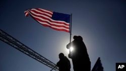 A man holds a American flag as supporters of President Donald Trump take part in the pledge as they stand in line for his rally outside the El Paso County Coliseum, Feb. 11, 2019, in El Paso, Texas. 