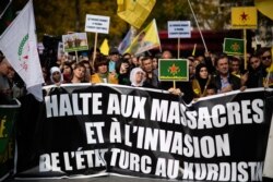 People hold pro-Kurd flags and banner in Paris, Oct. 12, 2019, during a demonstration to support Kurdish militants and protest as Turkey kept up its assault on Kurdish-held border towns in northeastern Syria.