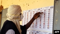 A voter wearing a mask checks the voters role at a polling station during the parliamentary elections in Gao, Mali, March 29, 2020. 