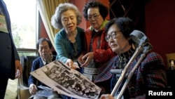 Para peserta reuni keluarga dari Korea Selatan melihat-lihat foto lama di sebuah hotel yang digunakan sebagai tempat menunggu di Sokcho, Korea Selatan (19/10). (Reuters/Kim Hong-Ji)
