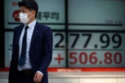 A man walks past an electronic stock board showing Japan's Nikkei 225 index at a securities firm in Tokyo, April 30, 2020.