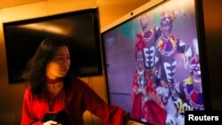 一名女子在北京一家海底捞餐厅和家人吃年夜饭时观看央视春节晚会。（2021年2月11日）