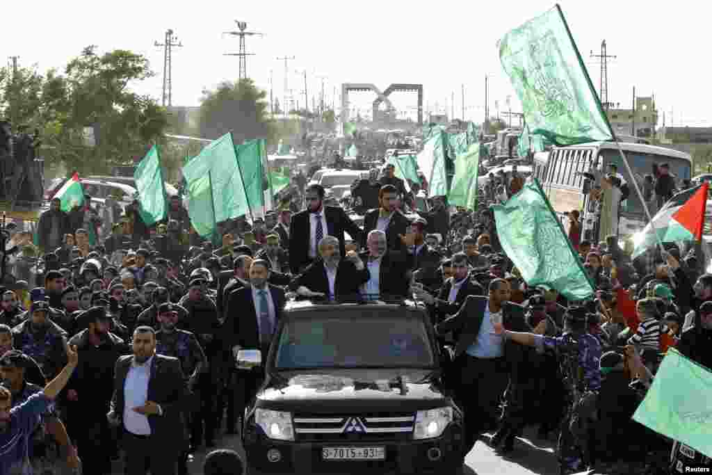 Hamas chief Khaled Meshaal (L), rides in a car with senior Hamas leader Ismail Haniyeh (R), and waves to the crowd upon his arrival in the southern Gaza Strip, December 7, 2012. 