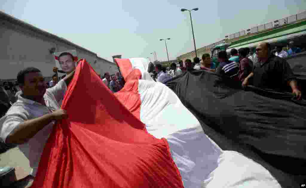 Supporters of Egypt's deposed president Hosni Mubarak wave a large national flag in front of Torah Prison in Cairo, August 22, 2013. 