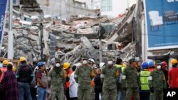 Rescue workers and volunteers stand in the middle of the street after an earthquake alarm sounded and a small tremor was felt during rescue operations at the site of a collapsed building in Roma Norte, in Mexico City, Saturday, Sept. 23, 2017. 