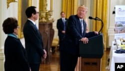 President Donald Trump speaks during an event about the Paycheck Protection Program used to support small businesses during the coronavirus outbreak, April 28, 2020, as Jovita Carranza, SBA administrator, and Treasury Secretary Steven Mnuchin listen.