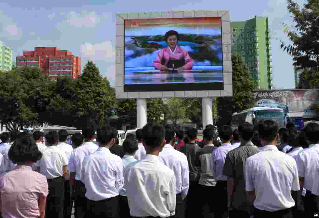 북한 관영 조선중앙TV 아나운서가 &#39;화성-14형&#39; 시험발사 성공을 발표하는 장면을 평양 주민들이 &nbsp;대형 스크린으로 시청하고 있다.