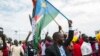 People gather as they wait for the arrival of South Sudan's President Salva Kiir in the capital Juba on Aug. 6, 2018, following the signing in neighboring Sudan of a cease-fire and power-sharing agreement. 