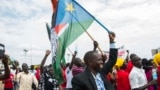 People gather as they wait for the arrival of South Sudan's President Salva Kiir in the capital Juba on Aug. 6, 2018, following the signing in neighboring Sudan of a cease-fire and power-sharing agreement. 