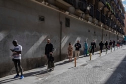 People use social distancing to prevent the spread of coronavirus, as they queue to enter a supermarket in Madrid, April 8, 2020.