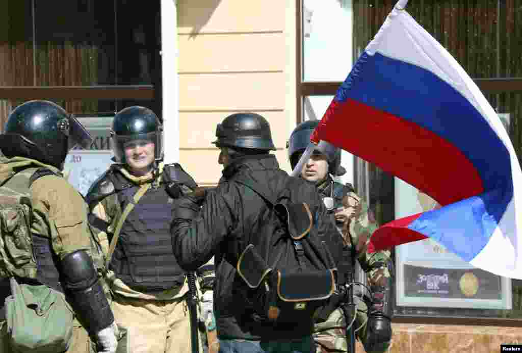Members of a Crimean self-defense unit speak with a motorcyclist waving a Russian flag in Simferopol, Crimea, Ukraine, March 17, 2014. 
