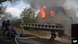 Firefighters try to extinguish a burning private house after shelling in the city of Donetsk, eastern Ukraine, Oct. 5, 2014. 