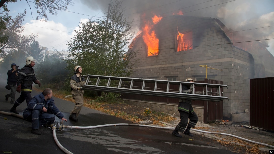 Petugas pemadam kebakaran berusaha memadamkan rumah yang terbakar akibat serangan artileri di Donetsk, Ukraina timur Minggu (5/10).