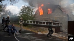 Petugas pemadam kebakaran berusaha memadamkan rumah yang terbakar akibat serangan artileri di Donetsk, Ukraina timur Minggu (5/10).