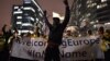 A man raises his hands during a protest in support of a new EU migration policy, a day before an EU leaders' meeting, in Brussels, Belgium, Dec. 13, 2017.