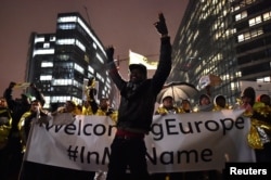 A man raises his hands during a protest in support of a new EU migration policy, a day before an EU leaders' meeting, in Brussels, Belgium, Dec. 13, 2017.