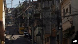 An elite police officer, bottom left, patrols one day after police came under fire during a shift change in the Alemao slum complex in Rio de Janeiro, Brazil, July 16, 2018. Rio is experiencing a wave of violence as gangs vie for control and police strugg