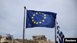A European Union flag flutters as the ancient Parthenon temple is seen in the background in Athens, June 1, 2015. 