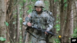 In a May 9, 2012 photo, Capt. Sara Rodriguez of the 101st Airborne Division walks through the woods during the expert field medical badge testing at Fort Campbell, Ky., on May 9, 2012.