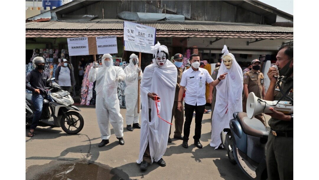 Pejabat pemerintah berpakaian pocong untuk mewakili para korban Covid-19 di sebuah pasar di Tangerang, 16 September 2020. (Foto : AP)
