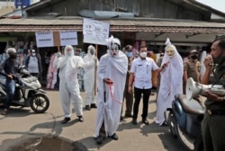 Pegawai pemerintah, di antaranya ada yang mengenakan kostum hantu 'pocong', memperingatkan bahaya Covid-19 di sebuah pasar di Tangerang, Banten (foto: dok).