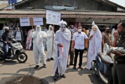 Pejabat pemerintah berpakaian pocong untuk mewakili para korban Covid-19 di sebuah pasar di Tangerang, 16 September 2020. (Foto : AP)