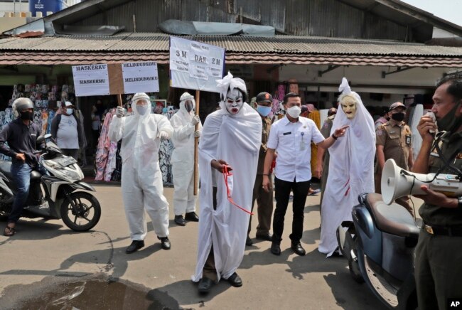 Pegawai pemerintah, di antaranya ada yang mengenakan kostum hantu 'pocong', memperingatkan bahaya Covid-19 di sebuah pasar di Tangerang, Banten (foto: dok).