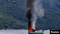 Perahu nelayan Vietnam yang tak berawak diledakkan oleh angkatan laut Indonesia, dan tenggelam di lepas pantai Natuna di Anambas, Kepulauan Riau, 5 Desember 2014. (Foto: REUTERS / Antara Foto / Immanuel Antoneus).