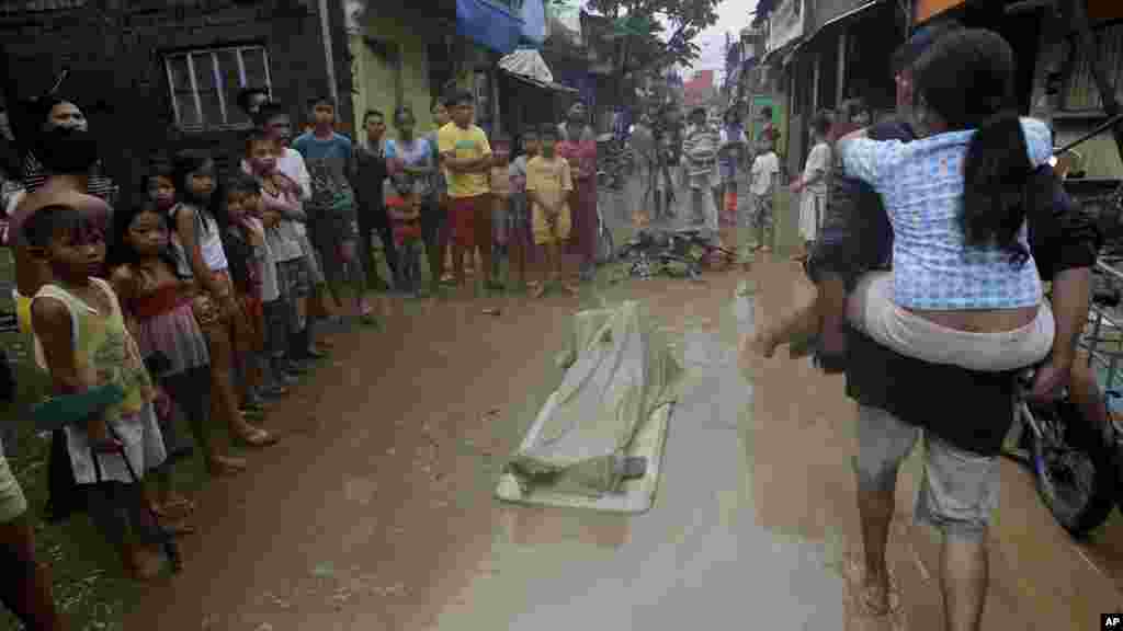 Residents gather around the body of a woman after being retrieved from the debris a day after massive flooding at Marikina city, east of Manila, Philippines, Sept. 20, 2014, 