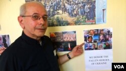 Reverend Peter P. Shyshka, principal of Saint George Academy, points out a hallway flyer that shows some of the Ukrainians who died in their country's conflict with pro-Russian separatists, New York, Sept. 10, 2014 (Adam Phillips/VOA).