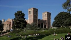 FILE - Students sit on the lawn near Royce Hall at UCLA in the Westwood section of Los Angeles on April 25, 2019. University of California, Los Angeles, officials have ordered all classes to be held remotely due to threats.