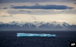 FILE - An iceberg floats past Bylot Island in the Canadian Arctic Archipelago, July 24, 2017. Shrinking icebergs and glaciers are contributing to global sea level rise.