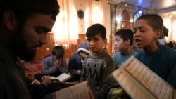 Sanam sits among Afghan boys as they read the Quran, Islam's holy book, during a class at a mosque, in Kabul, Afghanistan, Wednesday, Dec. 8, 2021.
