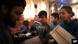 Sanam sits among Afghan boys as they read the Quran, Islam's holy book, during a class at a mosque, in Kabul, Afghanistan, Wednesday, Dec. 8, 2021.