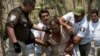 FILE - A Central American migrant is detained by Mexican immigration agents on the highway to Pijijiapan, Mexico, April 22, 2019. 