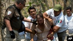 FILE - A Central American migrant is detained by Mexican immigration agents on the highway to Pijijiapan, Mexico, April 22, 2019. 