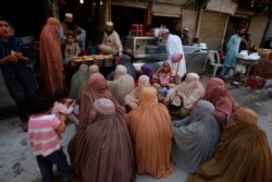 Perempuan muslim menunggu saat berbuka puasa Ramadan di luar sebuah toko roti di Peshawar, Pakistan, 24 April 2020.
