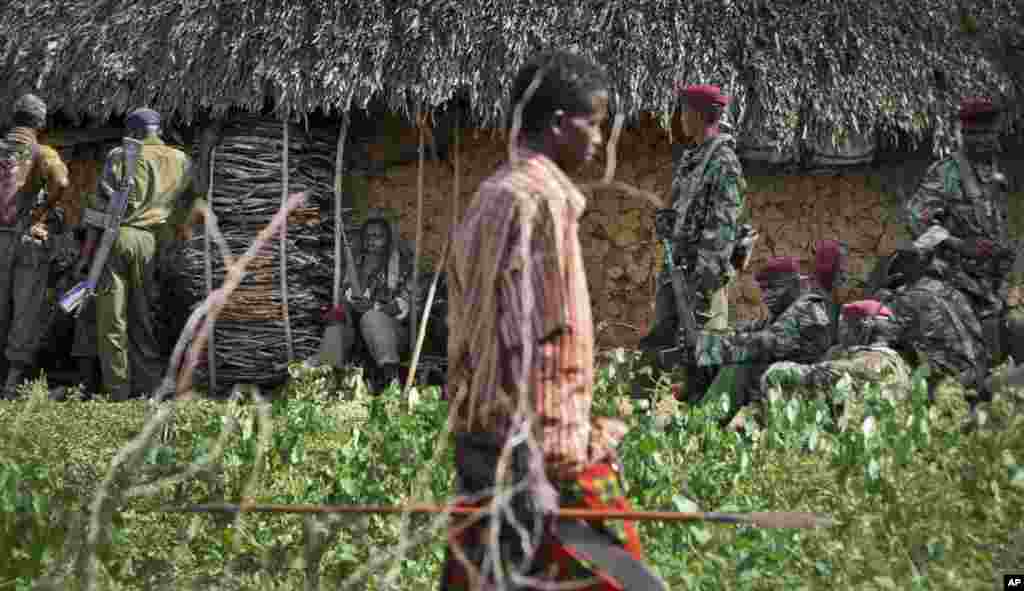 A villager armed with a spear walks past Kenyan police sent to keep order following tribal clashes in Kipao village in the Tana River Delta region of southeastern Kenya.