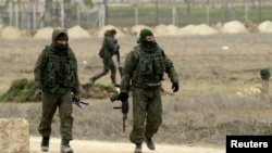 FILE - Armed men, believed to be Russian soldiers, are seen walking at the Crimean port of Yevpatoriya March 8, 2014.