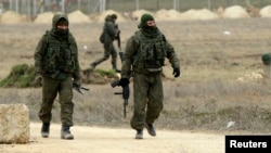 FILE - Armed men, believed to be Russian soldiers, are seen walking at the Crimean port of Yevpatoriya March 8, 2014.