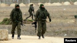 FILE - Armed men, believed to be Russian soldiers, are seen walking at the Crimean port of Yevpatoriya March 8, 2014.