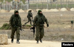 FILE - Armed men in unmarked uniforms, believed to be Russian soldiers, are seen walking at the Crimean port of Yevpatoriya March 8, 2014.