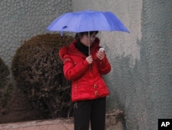 FILE - A North Korean woman uses a mobile phone on a sidewalk in Pyongyang, North Korea, March 16, 2012.