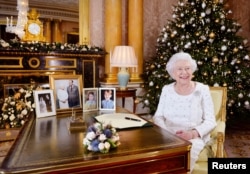 Britain's Queen Elizabeth sits at a desk in the 1844 Room after recording her Christmas Day broadcast to the Commonwealth, in Buckingham Palace, in this undated photograph received in London, Dec. 24, 2017.