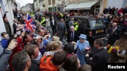 Ratu Elizabeth II (tengah) bersama Pangeran Philip disambut meriah oleh warga di kota Ennniskillen, Irlandia Utara (26/6).