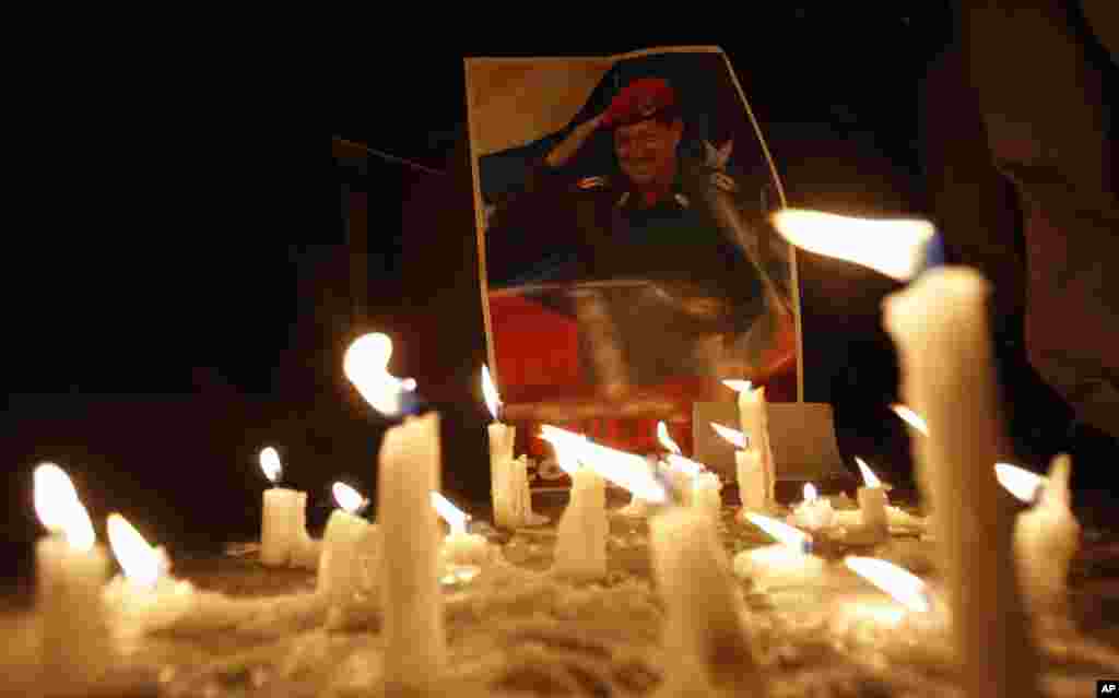 Candles, placed by mourner demonstrators, burn in front of an image of Venezuelan President Hugo Chavez outside Venezuela&#39;s embassy in Quito, Ecuador, March 5, 2013.