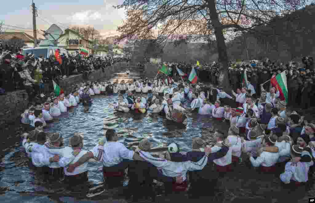 Bulgarians sing, play musical instruments and dance in the icy waters of the Tundzha river during Epiphany, in Kalofer.